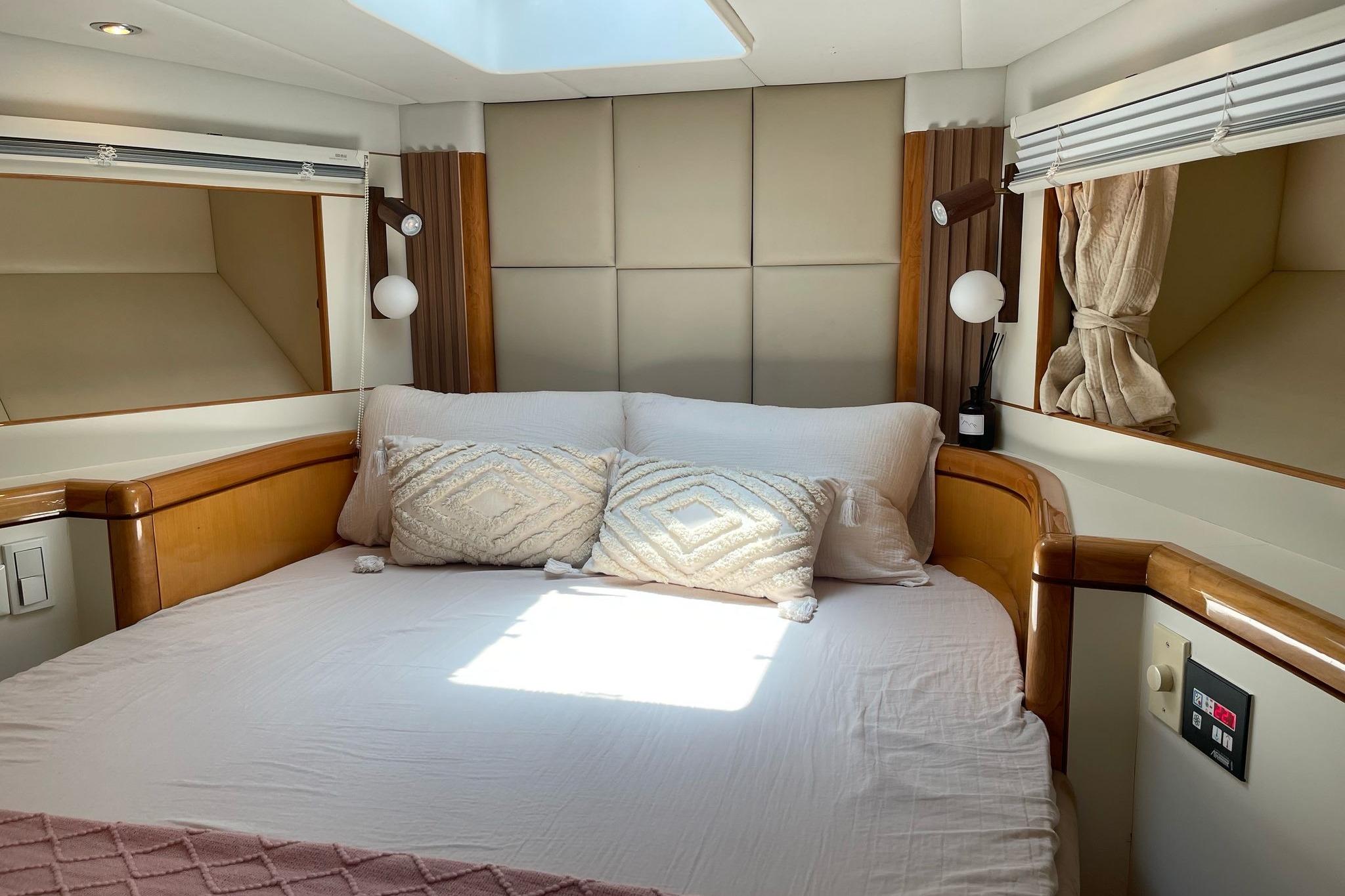 Luxurious bedroom interior of a 2007 Ruby 55 yacht with elegant bedding and wood accents.