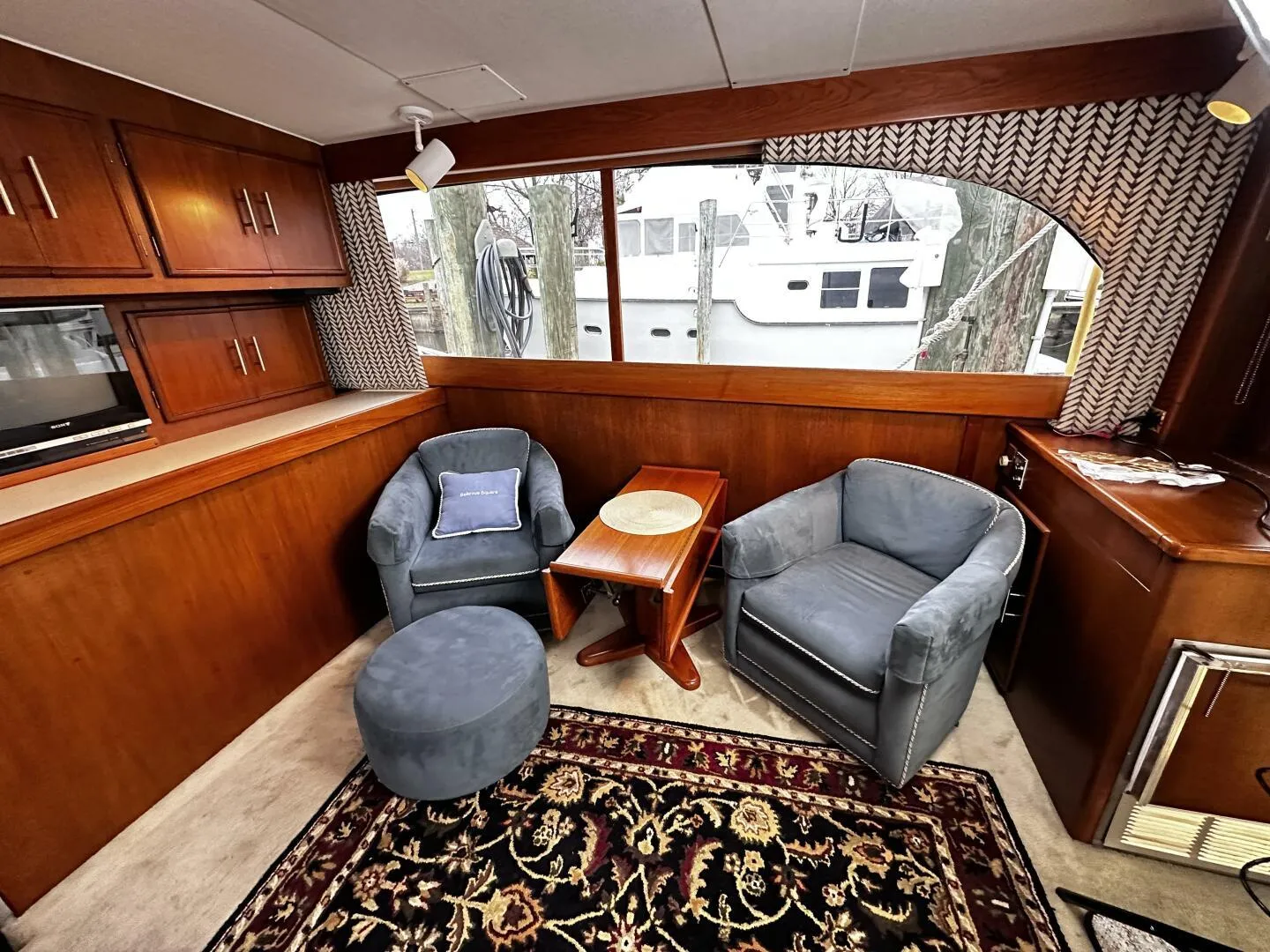 1985 Post 43 Sport Fisherman interior with cozy seating, wooden cabinets, and patterned rug.