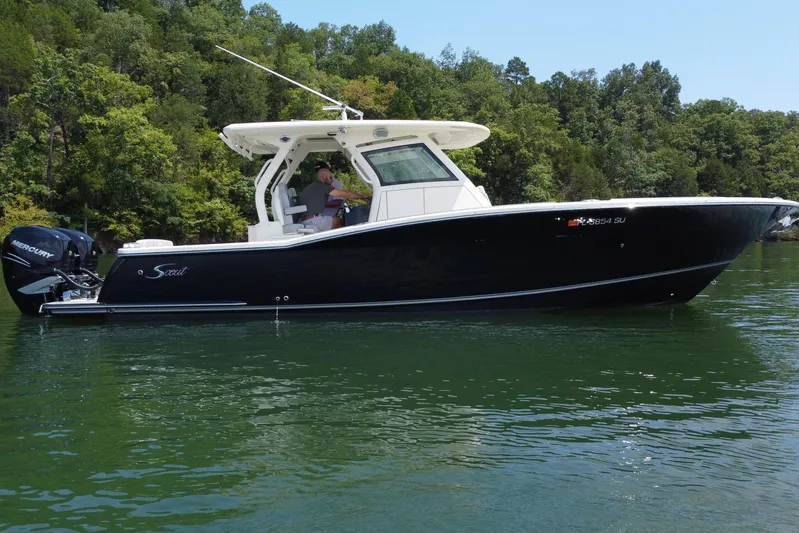  Yacht Photos Pics 2021 Scout 330 LXF boat on a serene lake with lush green trees.