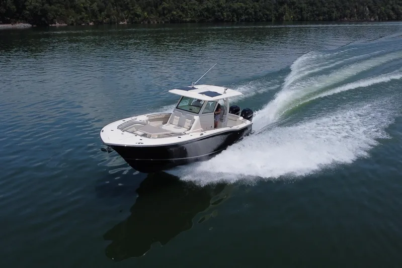  Yacht Photos Pics 2021 Scout 330 LXF boat cruising on a serene lake.