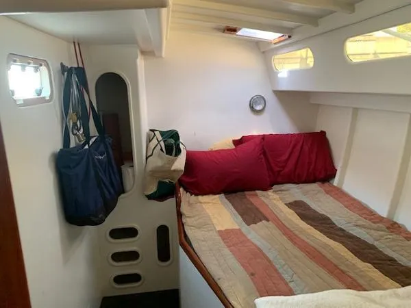  Yacht Photos Pics Cozy cabin interior of 1988 Ocean Custom boat with bed, portholes, and hanging bags.