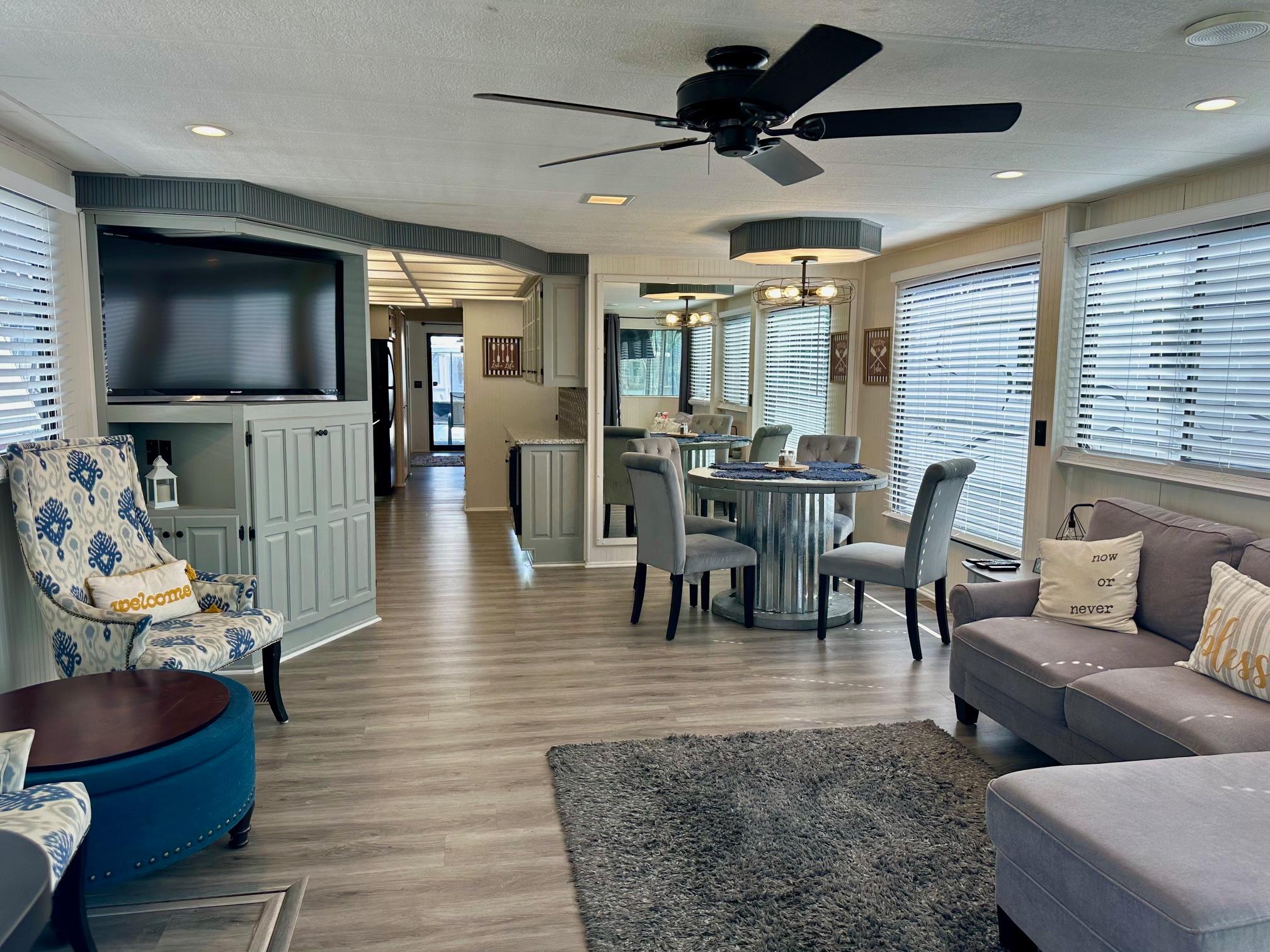 Spacious Lakeview 15x70 houseboat interior with modern decor, ceiling fan, and large windows.
