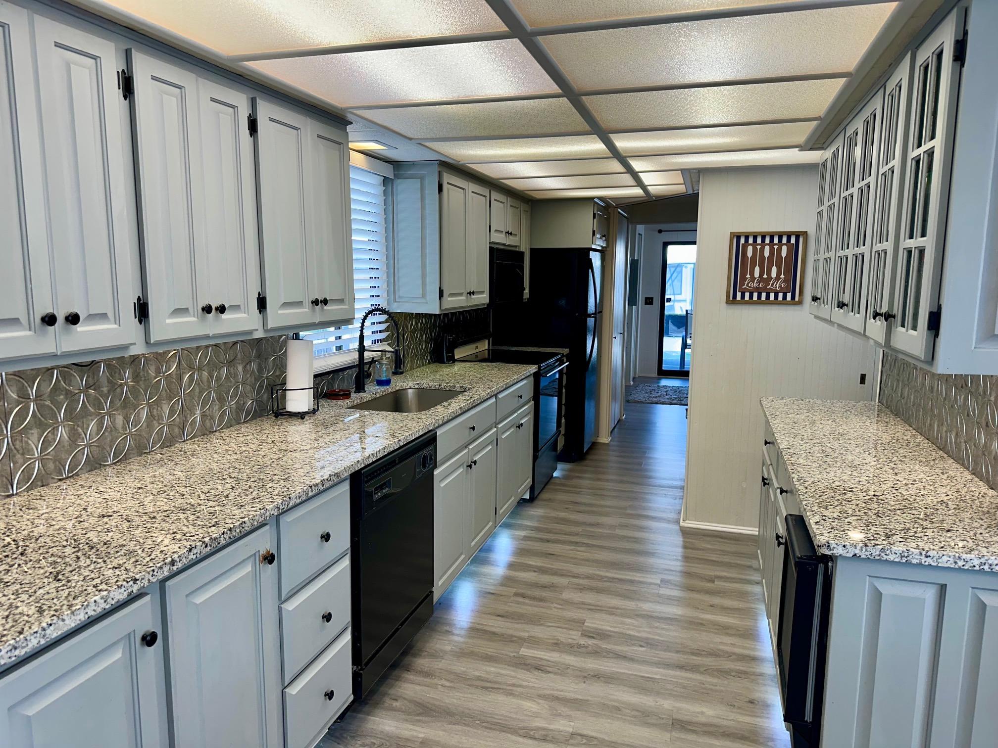 Modern kitchen with granite countertops, light cabinetry, and stainless steel appliances in a Lakeview 15x70 model.