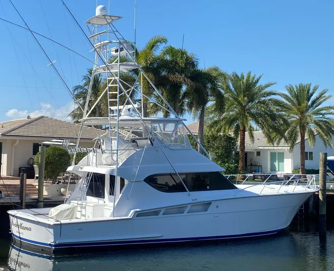 Rock Mama Yacht Photos Pics 2001 Hatteras 55 Convertible yacht docked near palm trees, under clear blue sky.