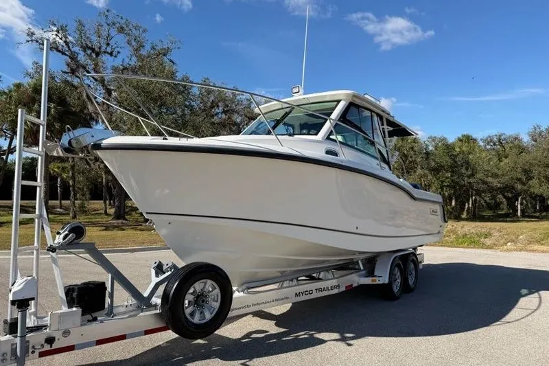 Yacht Photos Pics 2017 Boston Whaler 285 Conquest boat on trailer, parked outdoors under blue sky.