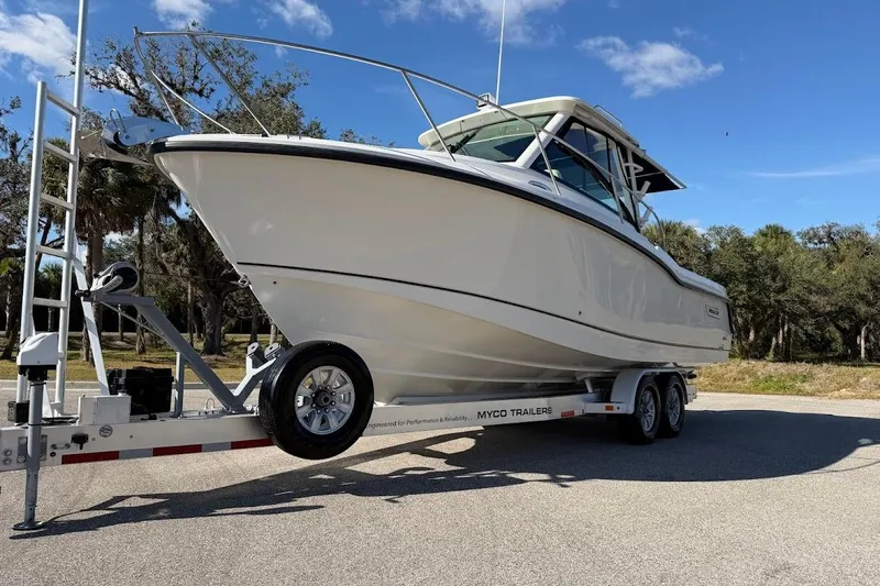  Yacht Photos Pics 2017 Boston Whaler 285 Conquest boat on trailer, parked outdoors under blue sky.