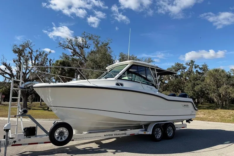  Yacht Photos Pics 2017 Boston Whaler 285 Conquest boat on trailer, parked outdoors under blue sky.