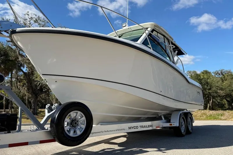  Yacht Photos Pics 2017 Boston Whaler 285 Conquest boat on trailer, parked outdoors under blue sky.