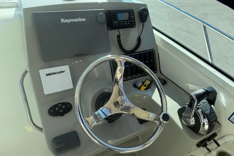  Yacht Photos Pics Control panel of a 2017 Boston Whaler 285 Conquest boat with steering wheel and navigation equipment.