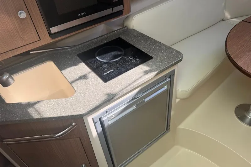  Yacht Photos Pics 2017 Boston Whaler 285 Conquest interior with kitchenette, featuring sink, stove, and seating area.