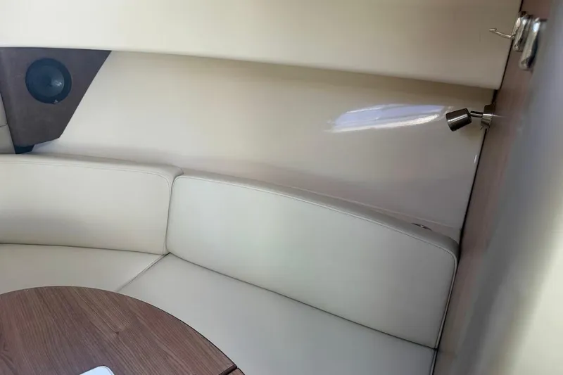  Yacht Photos Pics 2017 Boston Whaler 285 Conquest cabin interior with beige seating and wooden table.
