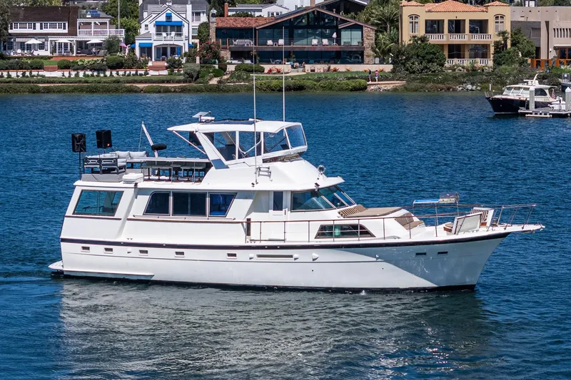 Maverick Yacht Photos Pics 1979 Hatteras 58 Motor Yacht cruising on a serene waterfront with houses in the background.