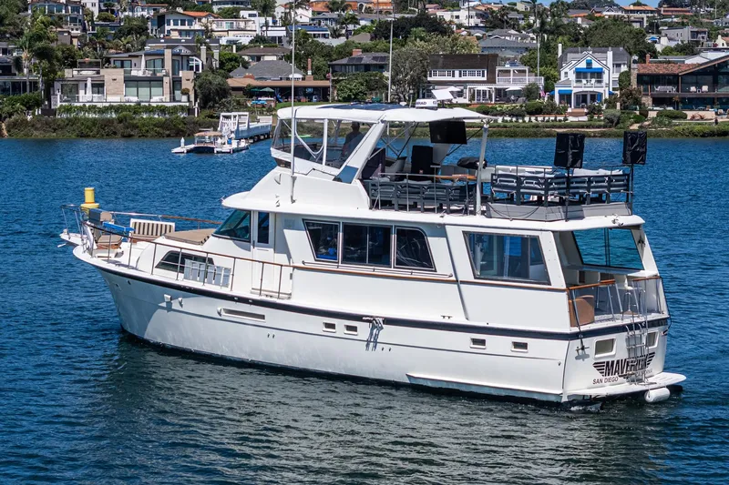 Maverick Yacht Photos Pics 1979 Hatteras 58 Motor Yacht cruising on a scenic waterfront with houses in the background.