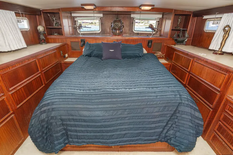 Maverick Yacht Photos Pics Luxurious bedroom interior of 1979 Hatteras 58 Motor Yacht with elegant wood cabinetry.