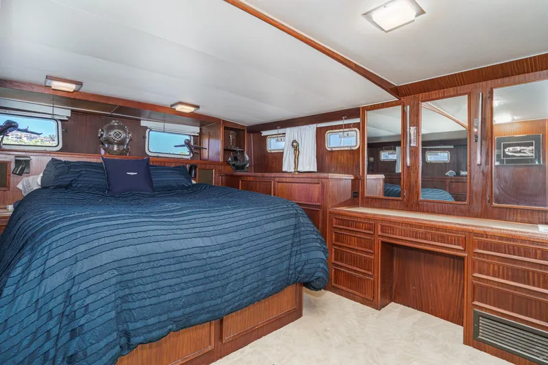Maverick Yacht Photos Pics Luxurious 1979 Hatteras 58 Motor Yacht bedroom with wood paneling and blue bedding.