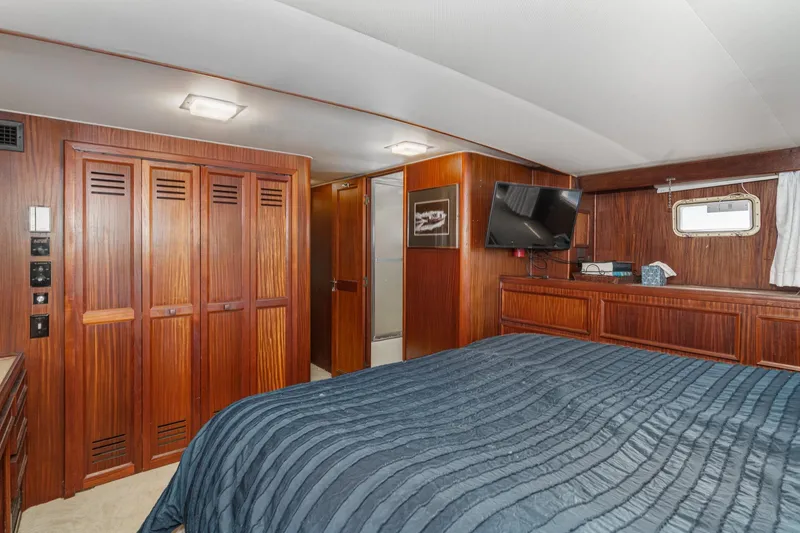 Maverick Yacht Photos Pics Luxurious 1979 Hatteras 58 Motor Yacht bedroom with wood paneling and modern amenities.