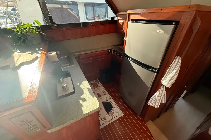 Wild Life Yacht Photos Pics 1989 Viking 45 Convertible yacht kitchen with stainless steel fridge, wooden cabinetry, and countertop plants.