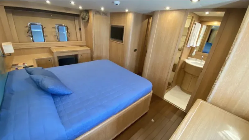  Yacht Photos Pics Luxurious 2008 Mangusta 72 yacht bedroom with blue bedding and ensuite bathroom.