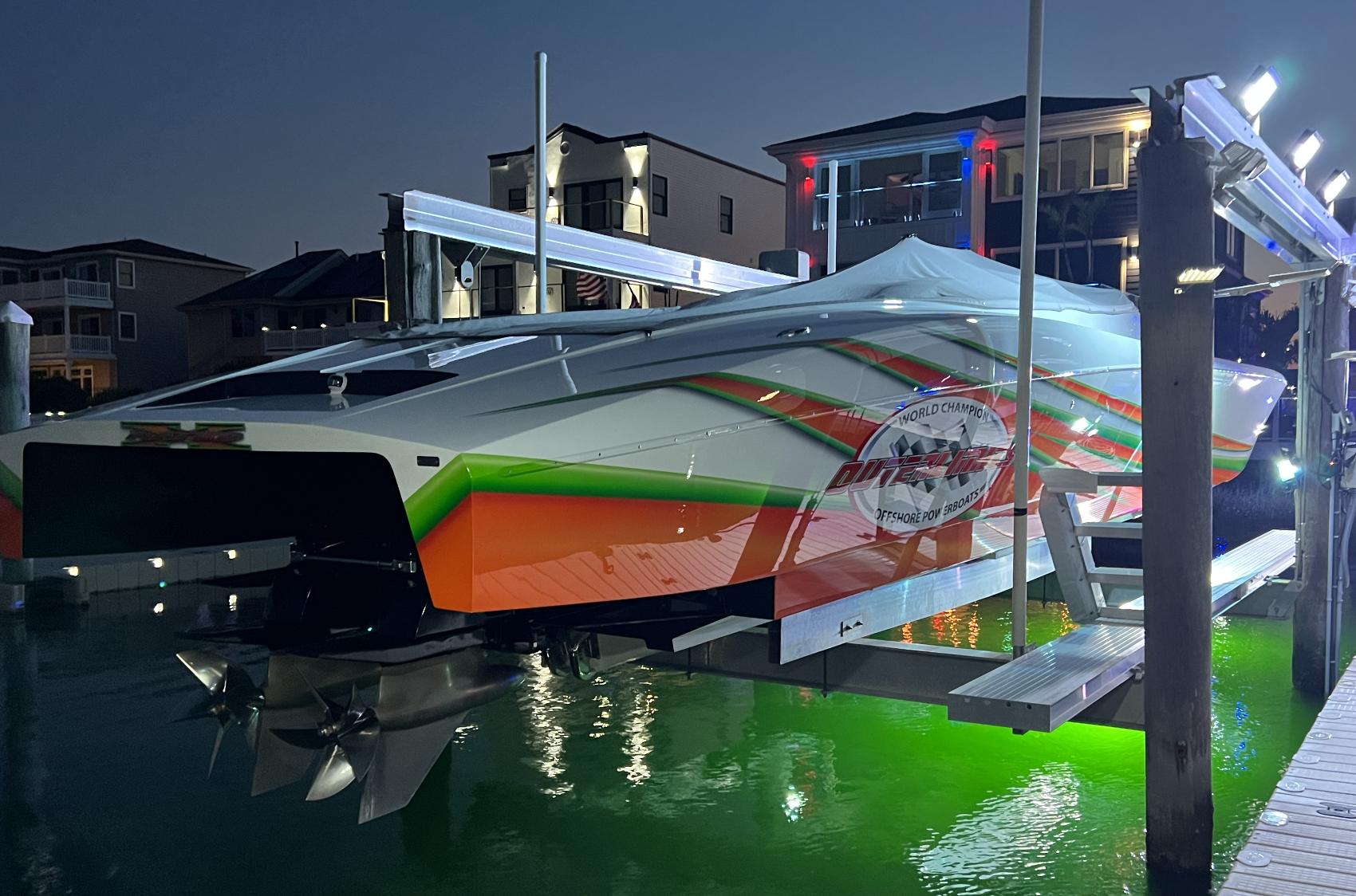2015 Outerlimits SL-50 powerboat docked at night with vibrant lighting.