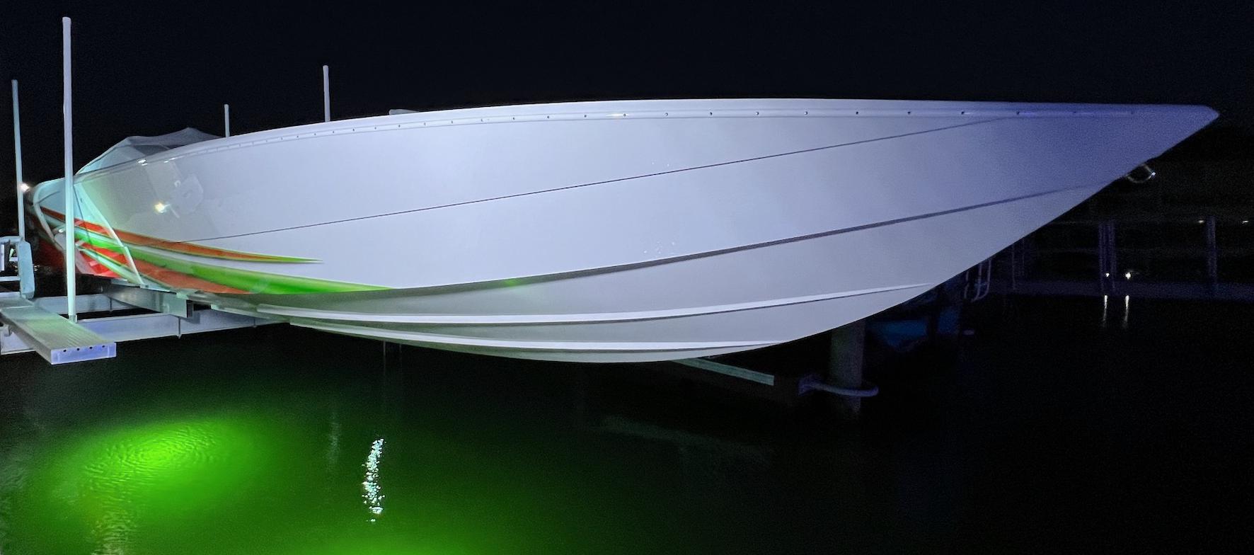 2015 Outerlimits SL-50 speedboat docked at night with green underwater lights.
