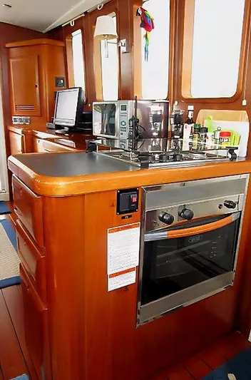 Aquavit Yacht Photos Pics 2006 Beneteau Swift Trawler 42 kitchen with stove, microwave, and wooden cabinetry.