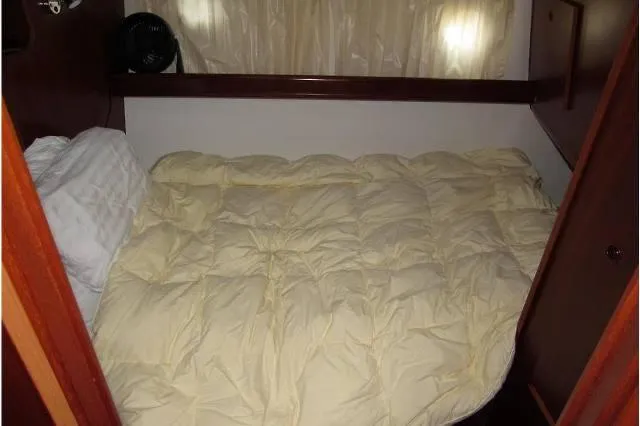 Aquavit Yacht Photos Pics Cozy cabin bed in 2006 Beneteau Swift Trawler 42 with soft bedding and wooden accents.