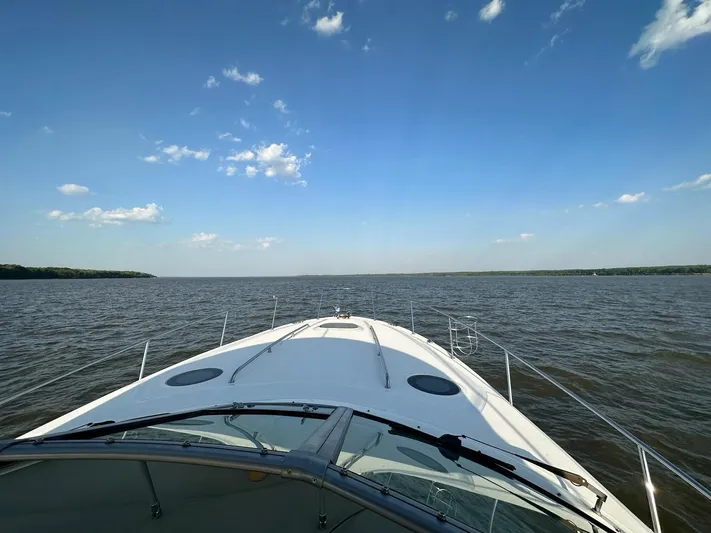  Yacht Photos Pics 2005 Sea Ray 340 Sundancer cruising on a calm lake under a clear blue sky.