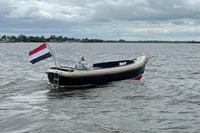 Interboat 21 Classic motorboat on a lake, flying a Dutch flag, cloudy sky.