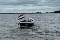 Interboat 21 Classic motorboat on a lake, flying a Dutch flag, cloudy sky.