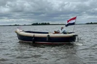 Interboat 21 Classic motorboat on a lake, flying a flag, under cloudy skies.