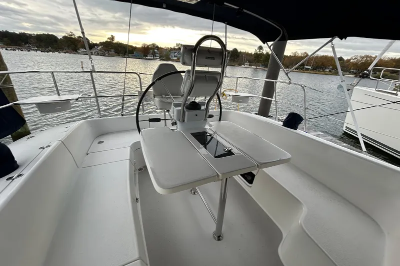  Yacht Photos Pics Cockpit of 2009 Catalina 375 sailboat with steering wheel and table, docked by a scenic waterfront.