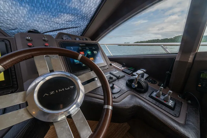Costa Luna Yacht Photos Pics Cockpit of 2014 Azimut 64 yacht with steering wheel and control panel, overlooking ocean.