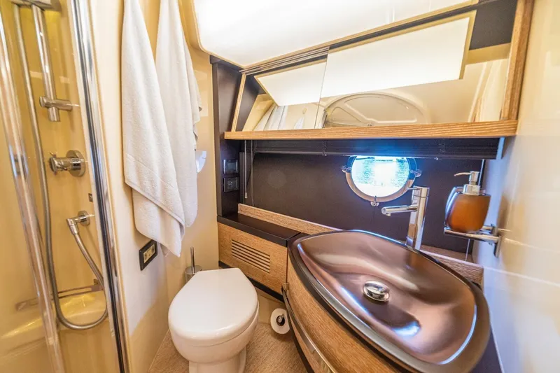 Costa Luna Yacht Photos Pics Luxurious bathroom in a 2014 Azimut 64 yacht with modern fixtures and porthole window.