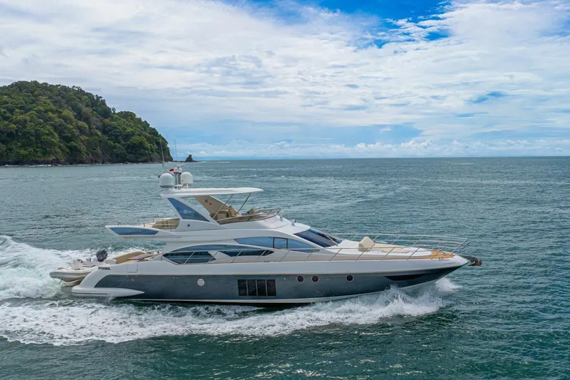 Costa Luna Yacht Photos Pics 2014 Azimut 64 yacht cruising on open sea near lush coastline.