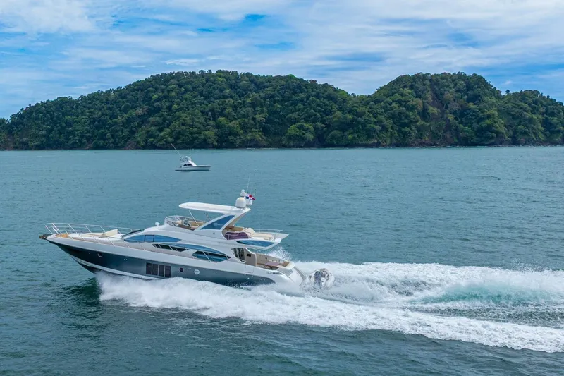 Costa Luna Yacht Photos Pics 2014 Azimut 64 yacht cruising on the ocean with lush green islands in the background.