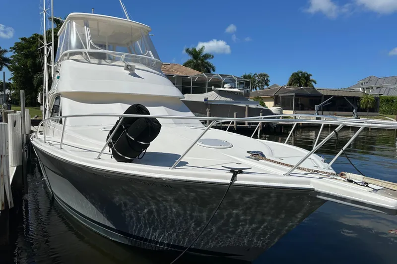 Game On Yacht Photos Pics 2002 Riviera 40 Flybridge yacht docked in sunny marina setting.