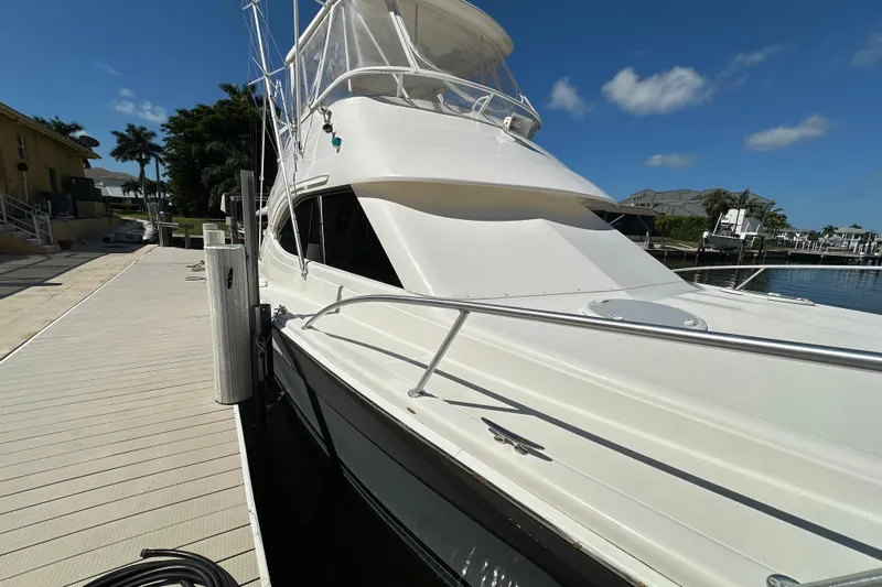 Game On Yacht Photos Pics 2002 Riviera 40 Flybridge yacht docked under clear blue sky.