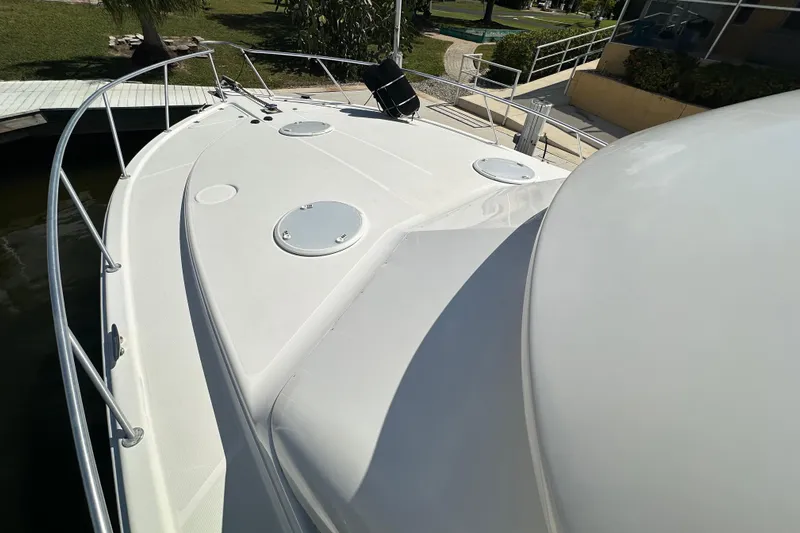 Game On Yacht Photos Pics 2002 Riviera 40 Flybridge yacht deck with railing, docked near greenery.