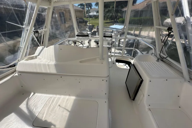 Game On Yacht Photos Pics 2002 Riviera 40 Flybridge interior with helm and seating area, featuring clear windows.