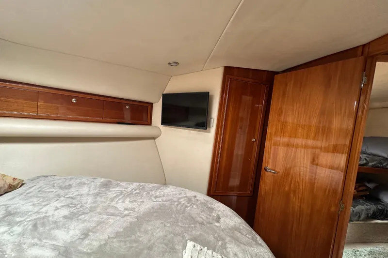 Game On Yacht Photos Pics Interior of 2002 Riviera 40 Flybridge yacht bedroom with wood paneling and TV.