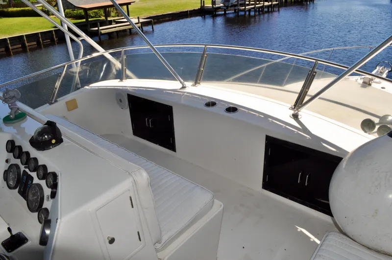 Freakin' Awesome Yacht Photos Pics 1990 Ocean Alexander 42 Sedan boat cockpit with control panel and seating, docked by a serene waterway.