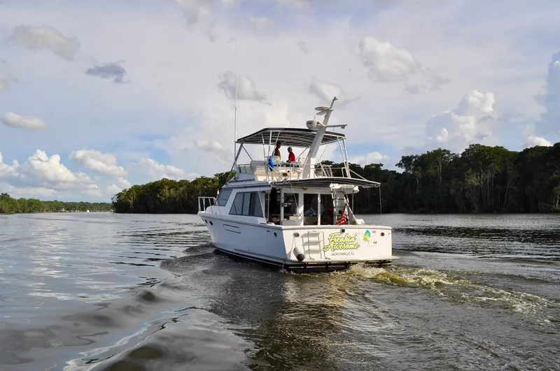 Freakin' Awesome Yacht Photos Pics Ocean Alexander 42 Sedan yacht cruising on a serene river, surrounded by lush greenery.