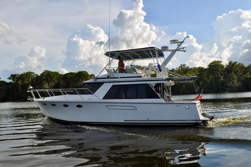 Freakin' Awesome Yacht Photos Pics 1990 Ocean Alexander 42 Sedan cruising on a calm river under a partly cloudy sky.