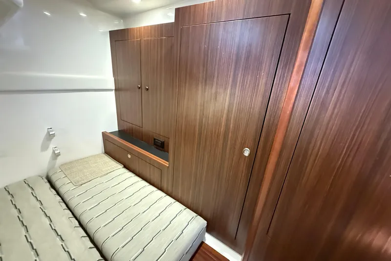 Bon Voyage Yacht Photos Pics 2019 Pursuit OS 355 Offshore cabin interior with wood paneling and striped bedding.