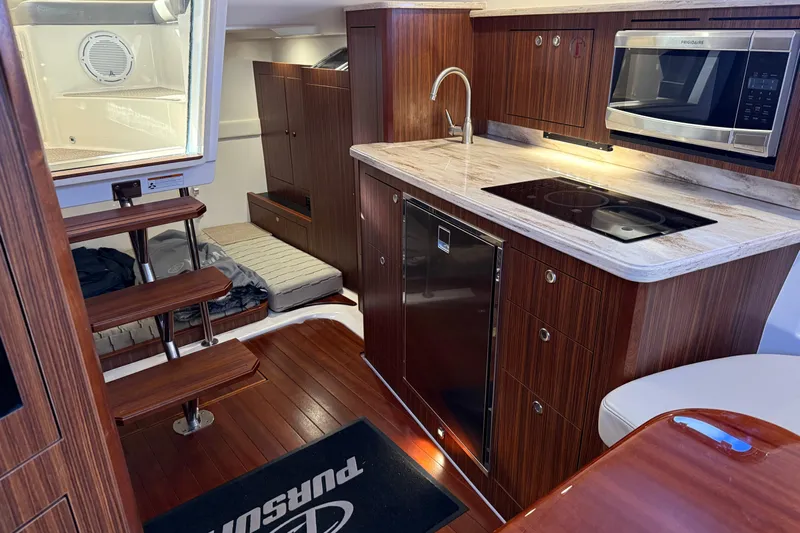 Bon Voyage Yacht Photos Pics Luxurious 2019 Pursuit OS 355 Offshore yacht interior with modern kitchen and wooden finishes.
