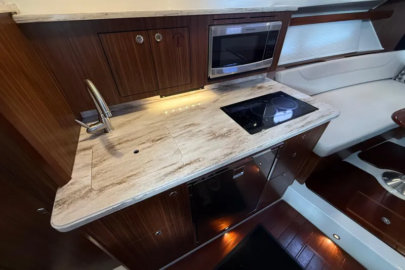 Bon Voyage Yacht Photos Pics 2019 Pursuit OS 355 Offshore yacht kitchen with modern appliances and elegant wood finish.