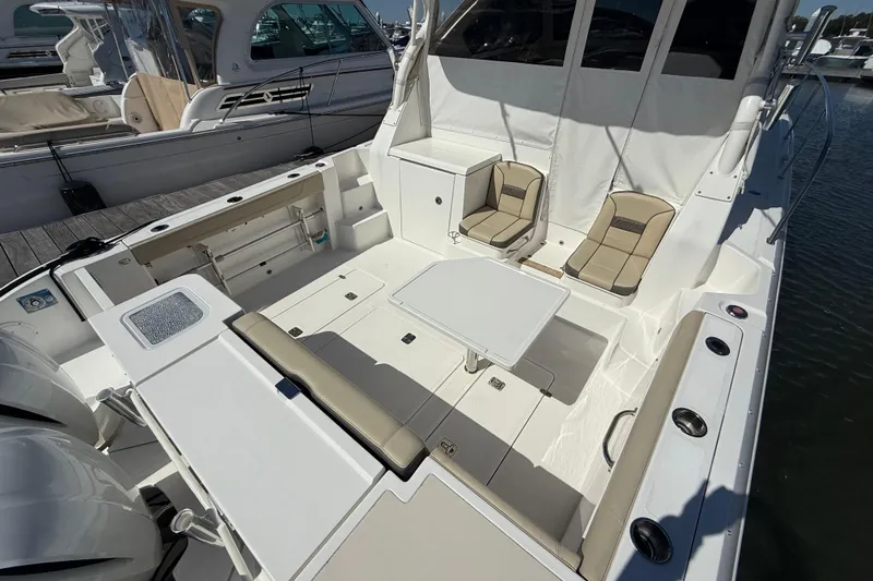 Bon Voyage Yacht Photos Pics 2019 Pursuit OS 355 Offshore boat interior with seating and table, docked at marina.
