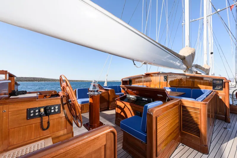 Meteor Yacht Photos Pics Luxurious 2007 Royal Huisman Schooner with elegant wooden deck and blue seating, sailing on open water.