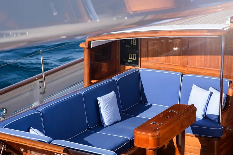 Meteor Yacht Photos Pics Luxurious seating area on 2007 Royal Huisman Schooner with blue cushions and wooden accents.