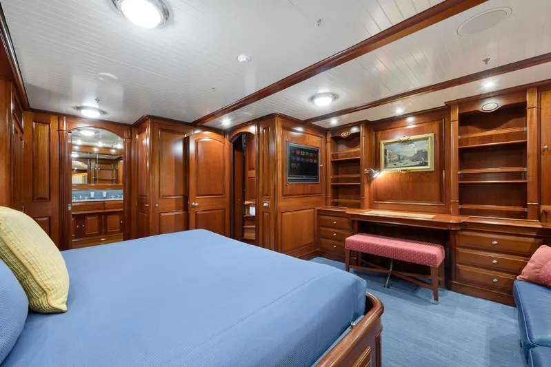 Meteor Yacht Photos Pics Luxurious wooden interior of 2007 Royal Huisman Schooner cabin with bed, desk, and shelves.